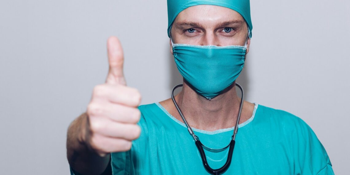 person in green crew neck long sleeve shirt wearing blue face mask