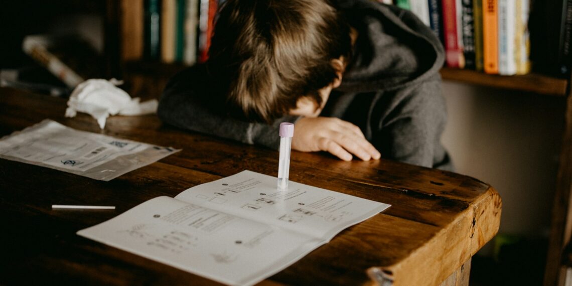 boy in gray hoodie reading book on brown wooden table