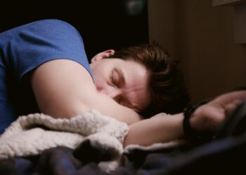woman in blue shirt lying on bed