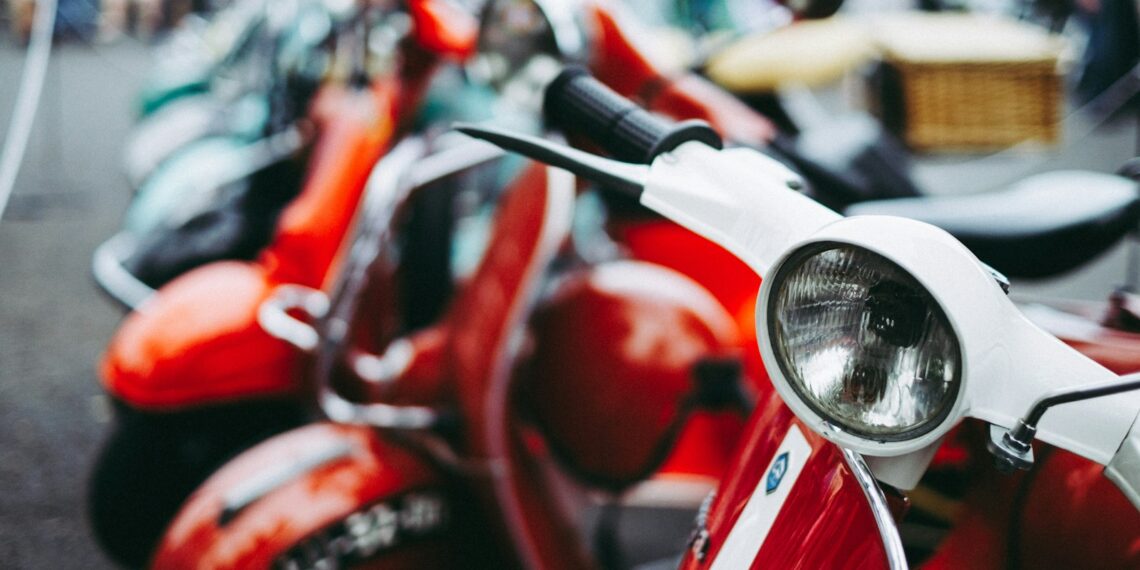 red and white motor scooter parked selective photography