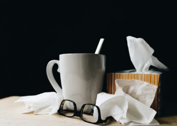 white ceramic mug on white table beside black eyeglasses
