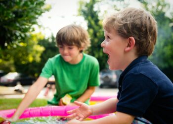 boy in blue shirt screaming near boy in green crew-neck shirt