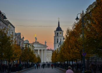 a group of people walking down a street next to tall buildings