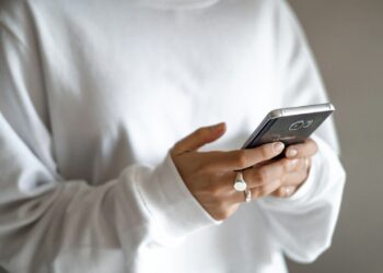 person in white long sleeve shirt holding black smartphone