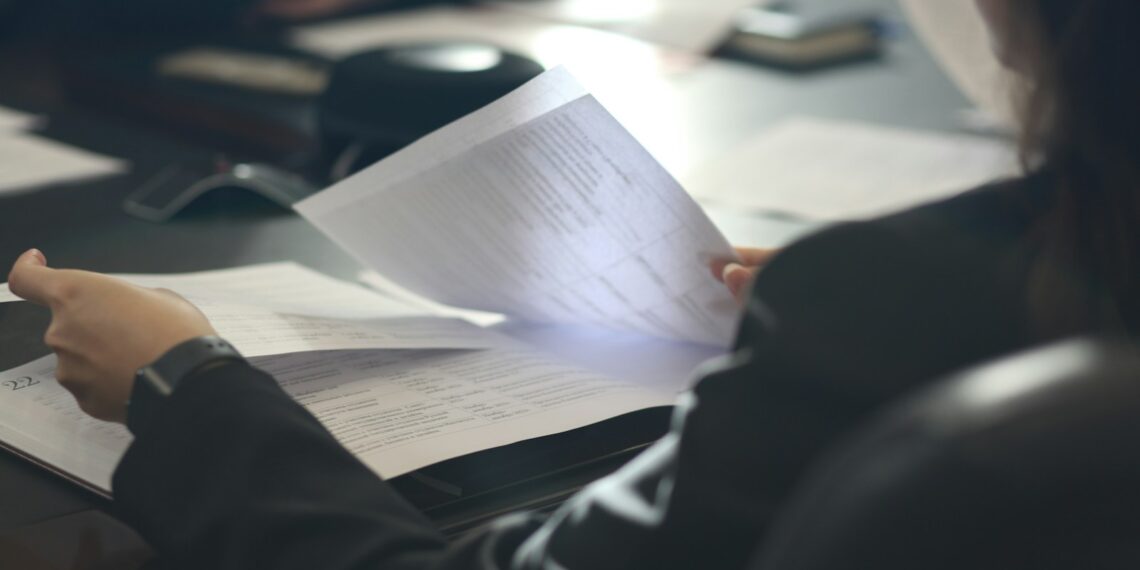 a woman sitting at a table reading a paper