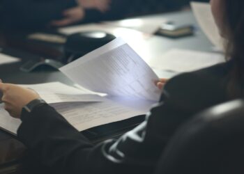 a woman sitting at a table reading a paper