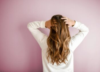 woman in white long-sleeved shirt standing in front of pink wall